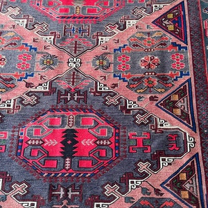 May include: A traditional rug with a geometric pattern in shades of pink, red, blue, and gray. The rug features intricate details and a central medallion.