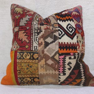 Puede incluir: Una funda de cojín de patchwork colorida con una variedad de patrones geométricos en tonos rojos, naranjas, marrones y blancos.