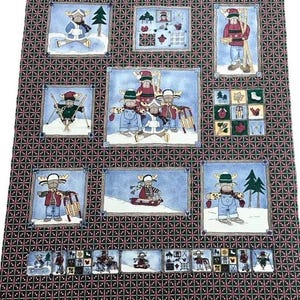 May include: A fabric panel featuring multiple winter-themed illustrations of moose in various activities like skiing and sledding. The illustrations are framed with a blue border and set against a black and red checkered background.