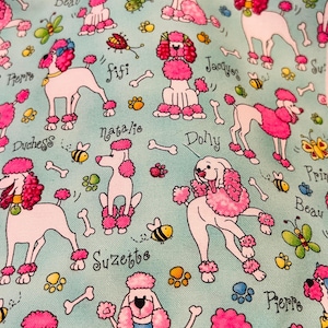 May include: Light blue fabric with a repeating pattern of white poodles with pink accents. The poodles are adorned with pink hair and accessories. Scattered around are bones, paw prints, bees, and butterflies. Names like "Princess" and "Fifi" are written on the fabric.