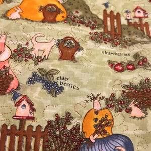 May include: A fabric with a whimsical design featuring figures in orange and pink dresses, cats, rabbits, birdhouses, and baskets. The words "strawberries" and "elder berries" are also visible. The background is a light green color.