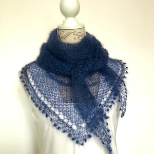 May include: A dark blue triangular shawl crafted from a fuzzy, open-knit yarn. The accessory features a delicate, airy texture with a decorative scalloped edge along the bottom border, showcasing a loose, hand-knitted construction style.