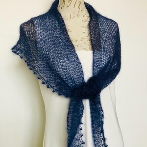 May include: A dark navy blue triangular shawl crafted from a fine, sheer, open-knit yarn. The accessory features a delicate, airy texture with small decorative loops along the edges and is tied in a simple knot at the center front of the display.