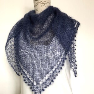May include: A dark blue triangular shawl crafted with a loose, open-knit texture. The garment features a delicate, airy construction with a decorative scalloped edge along the bottom border, showcasing a fine, fuzzy yarn finish throughout.