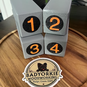 May include: Four gray wooden blocks with the numbers 1, 2, 3, and 4 in orange on black circles. A sticker with a black dog and the text "BADYORKIE WOODWORKING" is also visible.