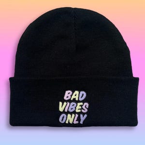 Könnte beinhalten: Schwarze Mütze mit einem bunten gestickten Aufnäher mit der Aufschrift "Bad Vibes Only".