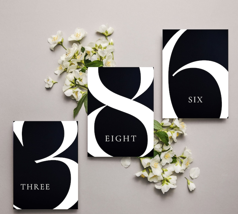 May include: Three black and white table number cards with the numbers "3", "6", and "8" in a stylized font. The numbers are written in white on a black background. The cards also include the words "THREE", "SIX", and "EIGHT" in white text below the numbers.