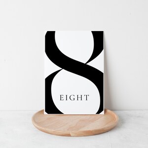 Puede incluir: Impresi&oacute;n de arte imprimible en blanco y negro con un n&uacute;mero ocho estilizado y la palabra "OCHO" debajo.