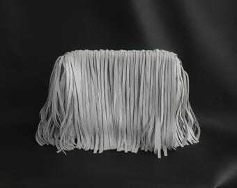 Peut inclure: Une pochette rectangulaire entièrement recouverte de longues bandes de franges gris clair. Les franges pendent verticalement depuis le bord supérieur, créant une texture dense et superposée qui masque le corps principal du sac. Design uniforme.