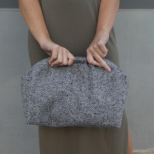 Puede incluir: Un bolso de mano de color blanco y negro con textura de espiga.