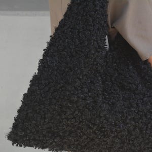 May include: A black fluffy tote bag made of faux fur. The bag is large and has a slouchy, unstructured shape.