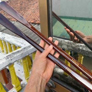 Pode incluir: Duas cal&ccedil;adeiras longas de madeira escura polida com um design liso e curvo. Uma cal&ccedil;adeira apresenta a palavra "His" gravada em letras douradas, enquanto a outra apresenta a palavra "Hers" gravada em letras douradas perto do cabo.