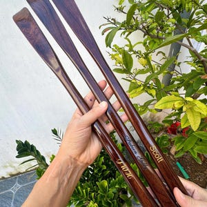 Pode incluir: Tr&ecirc;s cal&ccedil;adeiras longas de madeira castanho-escura com acabamento polido. Cada cal&ccedil;adeira apresenta um nome gravado em letras douradas: Scott, Fabien Gilly e J W H. As cal&ccedil;adeiras est&atilde;o unidas na base por um cord&atilde;o preto fino.