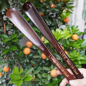 Pode incluir: Duas cal&ccedil;adeiras de madeira castanho-escura com um acabamento liso e polido. Cada cal&ccedil;adeira apresenta o texto gravado LYFE Man Of God numa fonte de cor clara ao longo do cabo. Os artigos t&ecirc;m uma forma curva e alongada para cal&ccedil;ado.