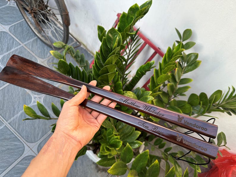 Pode incluir: Duas cal&ccedil;adeiras longas de madeira castanho-escura com acabamento polido. Cada cal&ccedil;adeira est&aacute; gravada com um nome, Matthew Whitaker e Tim Ray, e apresenta o texto Vendoroo com um pequeno &iacute;cone de coelho perto da extremidade do cabo.