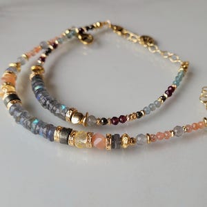Peut inclure: Deux bracelets de perles avec des détails dorés. L'un des bracelets présente un mélange de perles grises, jaunes et pêche. L'autre bracelet a une variété de perles colorées, dont des grises, rouges et bleues.