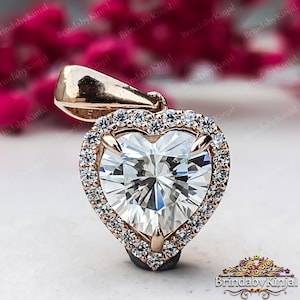 May include: A rose gold pendant featuring a heart-shaped clear cubic zirconia stone surrounded by a halo of smaller cubic zirconia stones.