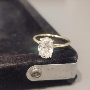 May include: A gold engagement ring with a large oval-shaped diamond.