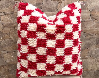 May include: Red and white checkered throw pillow with a fluffy texture. The pillow is made of a soft, woven material and has a square shape.