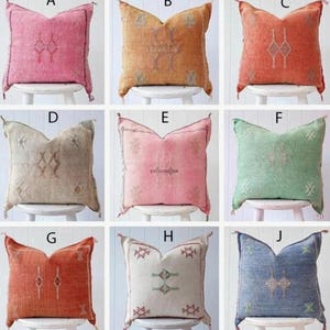May include: Nine different patterned throw pillows with tassels. The pillows are arranged in three rows of three. The pillows are all different colors and patterns, including pink, orange, green, blue, and beige.