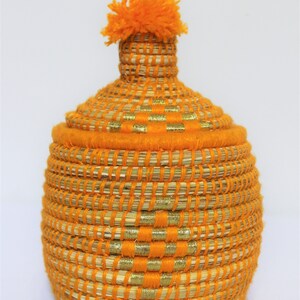 Peut inclure: Panier tiss&eacute; orange avec une bordure dor&eacute;e et un pompon orange moelleux sur le couvercle.