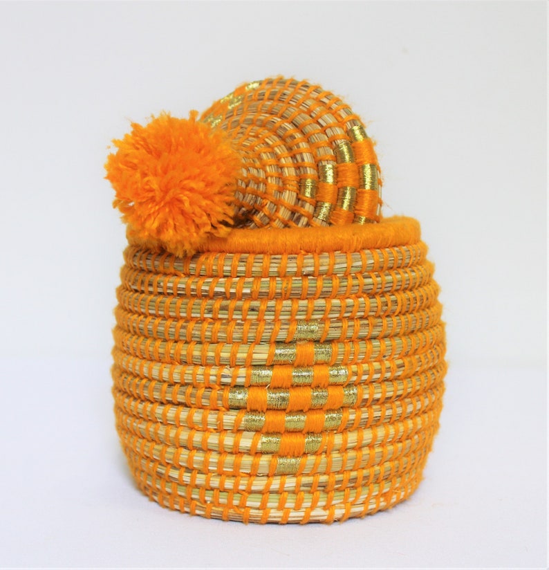 Peut inclure: Panier tiss&eacute; orange avec une bordure dor&eacute;e et un pompon orange moelleux sur le couvercle.