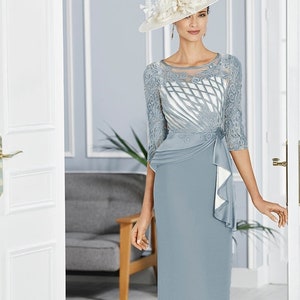 Rosa Clara Mother of the Bride cocktail dress in crepe sateen with lace on the bodice. Round neckline with three-quarter sleeves and beaded brooch at the waist.
Suitable for Mother of the Bride, Mother of the Groom,