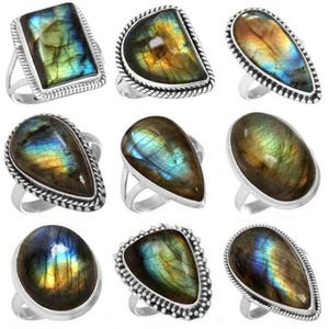 Könnte beinhalten: Neun silberne Ringe mit polierten Labradorit-Edelsteinen. Die Edelsteine zeigen schillernde Farben von Blau, Grün und Gold. Die Ringe haben verschiedene Formen, darunter oval, tropfenförmig und rechteckig, mit unterschiedlichen Fassungen.