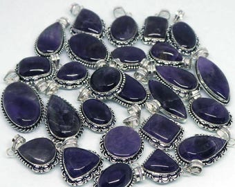 May include: A collection of amethyst gemstone pendants in various shapes, including oval, teardrop, and square. Each pendant has a silver-colored metal setting with intricate detailing. The gemstones are a deep purple color.