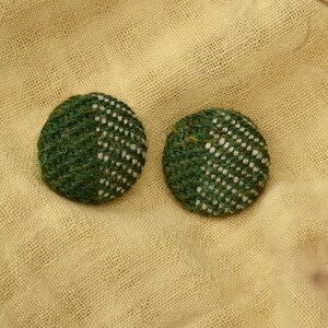 May include: Two green and white patterned fabric buttons. The buttons are round and have a woven texture.