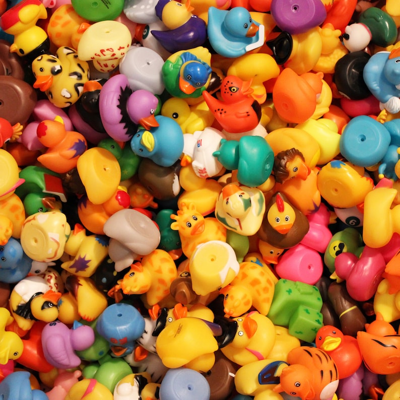 May include: A large collection of colorful rubber duck toys in various shapes and sizes. The ducks are made of a soft, flexible material and have a variety of designs, including animals, characters, and geometric shapes.