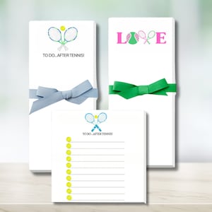 May include: Three white notepad sets with a tennis theme. One set features two crossed tennis rackets with a tennis ball, another set features the word "LOVE" with a tennis ball and two crossed rackets, and the third set features a checklist with tennis balls and two crossed rackets. The text on the notepads reads "To Do...After Tennis!"