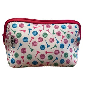May include: A white cosmetic bag with a red zipper and trim. The bag is patterned with pink, blue, and green golf tees and polka dots. The bag has a small tag on the side with the text "Born to Tee".