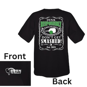 K&ouml;nnte beinhalten: Schwarzes T-Shirt mit einer wei&szlig;en Grafik eines Pickleball-Schl&auml;gers und eines Balls. Der Text auf der Grafik lautet "Dink Responsibly Don't Get Smashed! Est. 2021". Die Vorderseite des Shirts hat eine kleine wei&szlig;e Grafik eines Pickleball-Schl&auml;gers mit dem Text "Born to Rally".