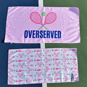 May include: Pink and white beach towel with a pink tennis racket and the text "OVERSERVED". The other side of the towel has a repeating pattern of pink tennis rackets and wine bottles.