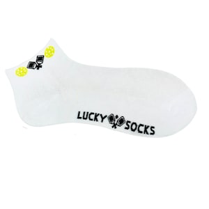 May include: White ankle socks with black and yellow graphics. The socks have a design of a black and yellow graphic on the top and the words "LUCKY SOCKS" in black on the side.