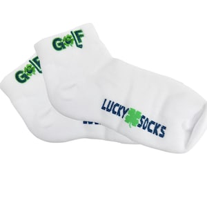 May include: A pair of white ankle socks with the word "GOLF" in green and a shamrock design. The words "LUCKY SOCKS" are printed in blue with a green shamrock. The socks are made of a soft, comfortable material.