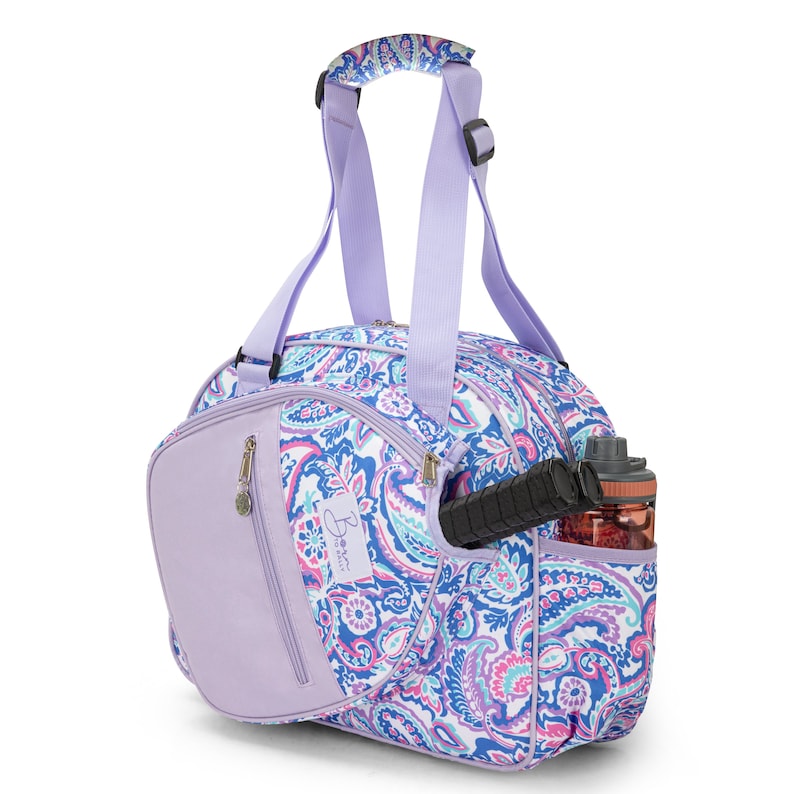 May include: A purple and white paisley patterned tennis bag with a separate compartment for a racket and a side pocket for a water bottle. The bag has a top handle and adjustable shoulder straps.
