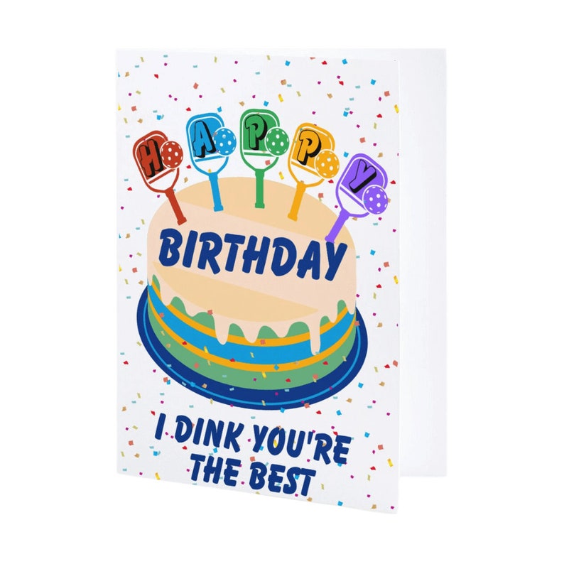 K&ouml;nnte beinhalten: Eine Geburtstagskarte mit einem Kuchen, der mit bunten Paddleball-Schl&auml;gern verziert ist, die "Happy Birthday" buchstabieren. Die Karte hat einen wei&szlig;en Hintergrund mit Konfetti und den Text "I Dink You're The Best".
