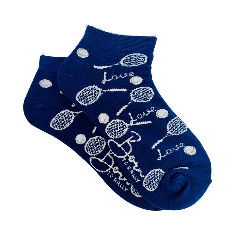 Puede incluir: Calcetines tobilleros azul marino con dise&ntilde;o de tenis. En los calcetines est&aacute;n impresas raquetas de tenis blancas, pelotas de tenis y la palabra "Love". Tambi&eacute;n est&aacute; impreso el texto "Born to Rally".