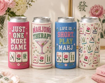 May include: Four cylindrical beverage can coolers featuring mahjong-themed designs. The first is pink with the text "JUST ONE MORE GAME" and mahjong tiles. The second is white with "MAHJONG THERAPY" and a martini glass. The third is blue with "LIFE IS SHORT, PLAY MAHJ" and tiles. The fourth is cream with a pattern of mahjong tiles.
