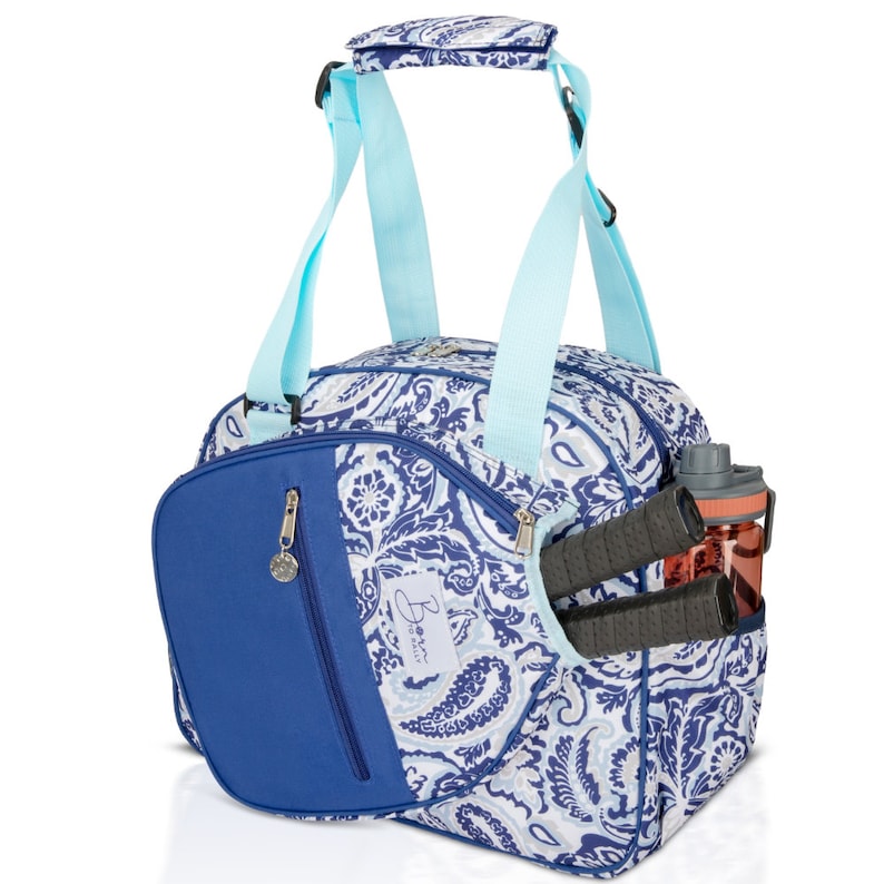 May include: A blue and white paisley patterned sports bag with a blue zippered pocket and a blue and turquoise handle. The bag has a side pocket for a water bottle and a separate pocket for a racket.