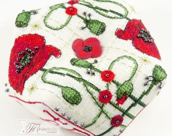 May include: A square, off-white fabric item with embroidered red poppies and green leaves. The design includes small red flowers and beaded accents. The item has a stitched border and the designer's logo in the corner.