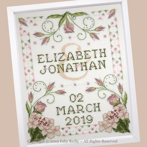 May include: Framed cross-stitch artwork featuring the names "ELIZABETH & JONATHAN" and the date "02 MARCH 2019". The design includes floral elements in pink and green, with a white frame. Copyright 2019 Faby Reilly ~ All Rights Reserved.
