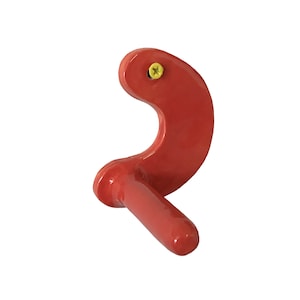 Puede incluir: Gancho de metal rojo con un pequeño mango. El gancho está fijado a una pared con un tornillo.