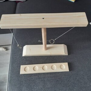 May include: Wooden ring toss game with a base, a vertical post, and a horizontal bar. The game has five holes for the rings to land in.