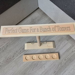 May include: Wooden game with a sign that reads "Perfect Game For a Bunch of Tossers" and five holes for tossing rings.