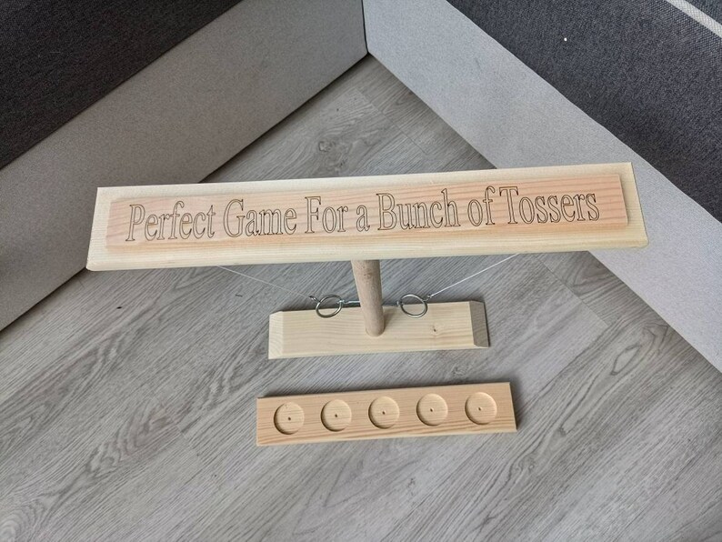 May include: Wooden game with a sign that reads "Perfect Game For a Bunch of Tossers" and five holes for tossing rings.