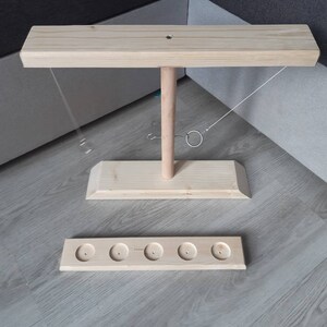 May include: Wooden ring toss game with a base, a vertical post, and a horizontal bar. The game includes five rings and a string attached to the bar.