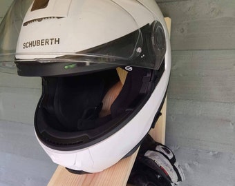 May include: A white motorcycle helmet with a black visor and the word "SCHUBERTH" printed on the side. The helmet is mounted on a wooden shelf with a pair of black and red motorcycle gloves.